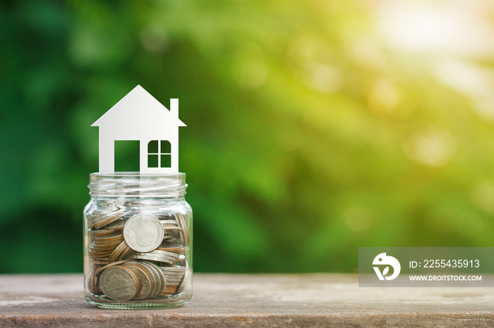 House model on coins in glass jar, saving to buy a house