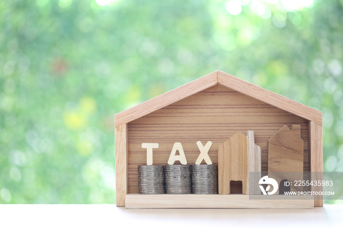 Estate tax,Model house with stack of coins money and tax word on green background,Business investment and Property tax concept