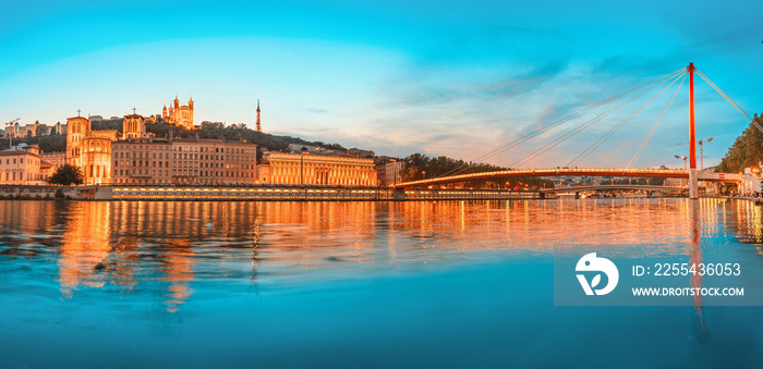 Lyon night cityscape with illuminated Courthouse and red pedestrian bridge over Saone river. Panoramic blue hour landscape