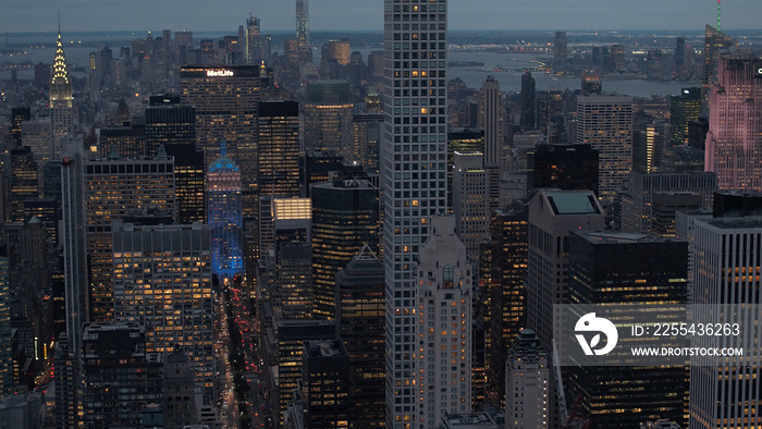 AERIAL: New York City skyscrapers and busy streets lit up with lights at night