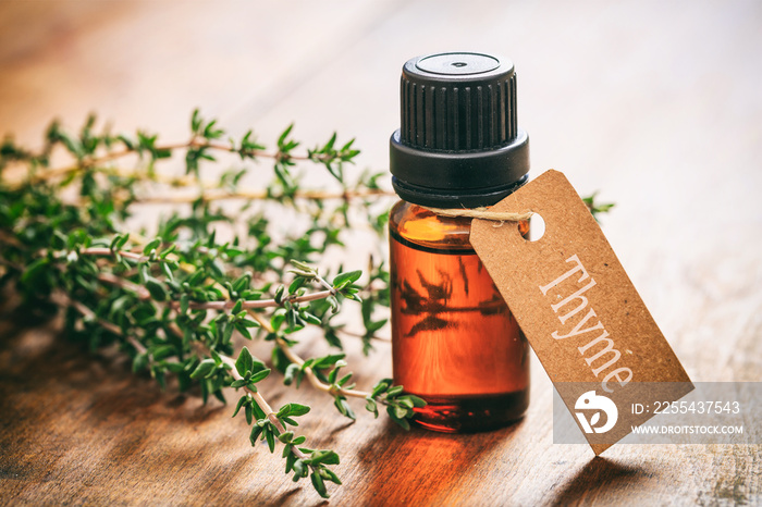 Thyme oil on wooden background, tag with text