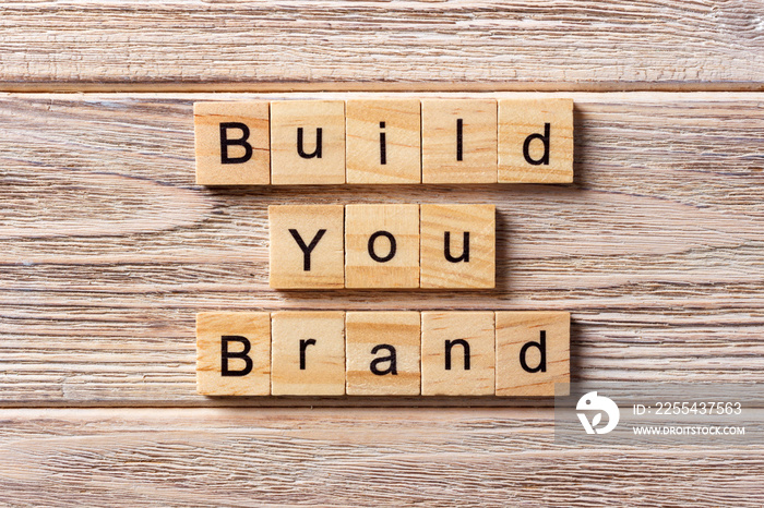 BUILD YOUR BRAND word written on wood block. BUILD YOUR BRAND text on table, concept