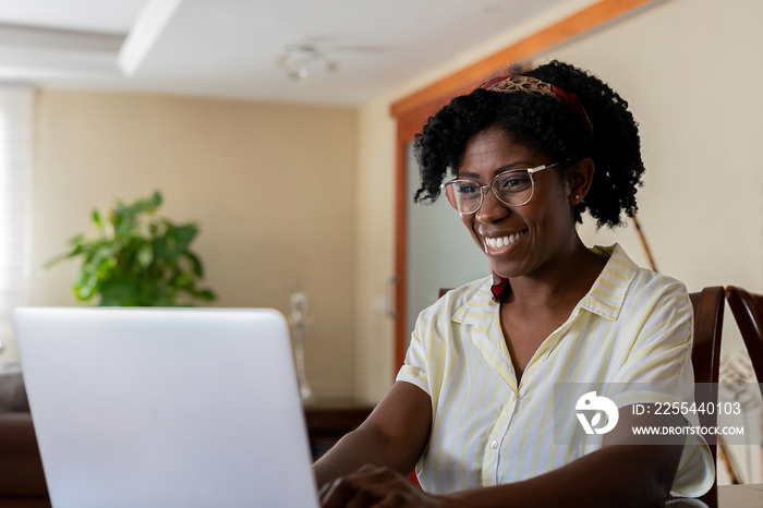 Cheerful black freelancer using laptop at home