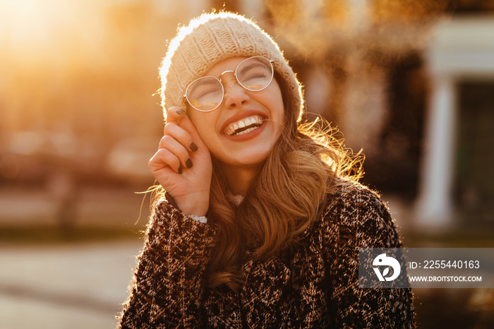 Enthusiastic european girl touching her glasses. Excited female model posing in autumn evening.