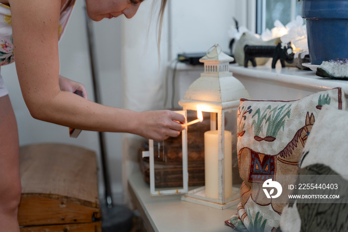 Woman igniting candle in lantern