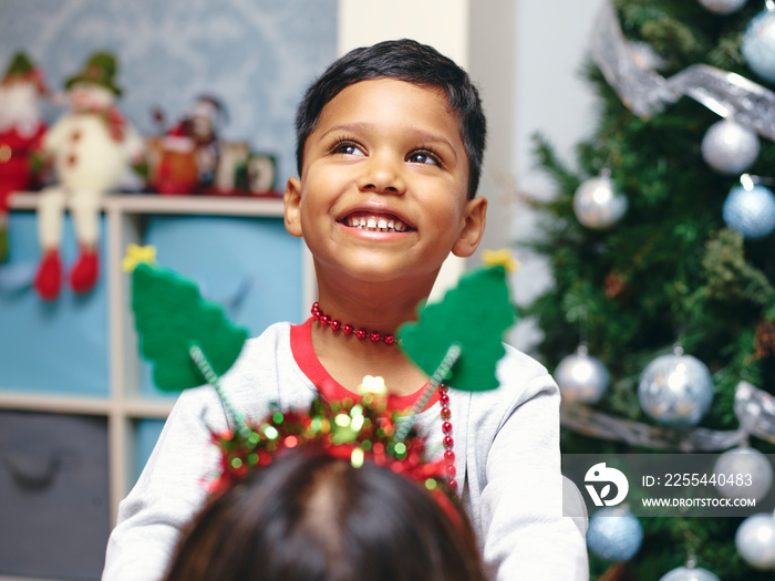 Boy putting Christmas headband on mother