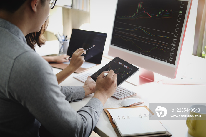 An investment expert points a pen at a computer monitor to analyze the stock market to teach you how to make a profit.