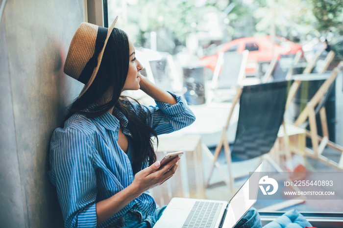 Woman using devices for remote work on windowsill