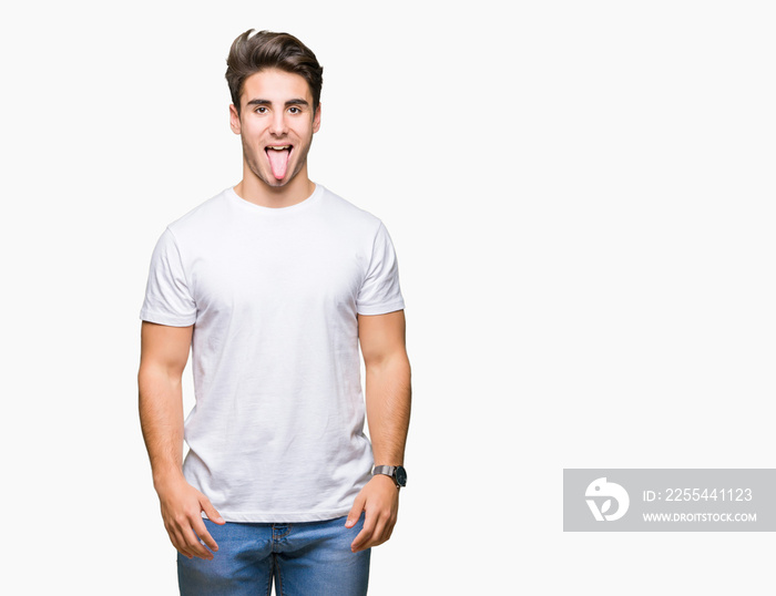 Young handsome man wearing white t-shirt over isolated background sticking tongue out happy with funny expression. Emotion concept.