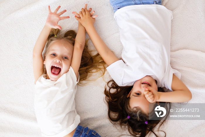 happy little girls lying on back top view sisters