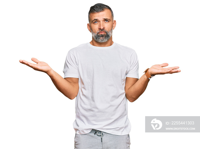 Middle age handsome man wearing casual white tshirt clueless and confused with open arms, no idea concept.