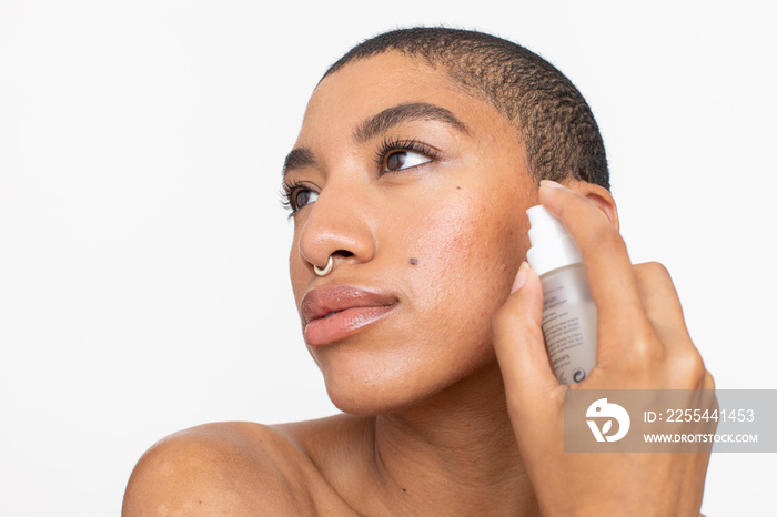 Studio portrait of woman applying face serum