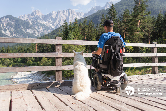 Disabled man on wheelchair with his dog on a trip in nature.