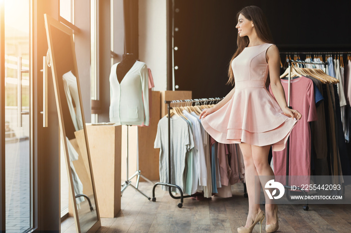 Smiling woman trying on dress at mirror