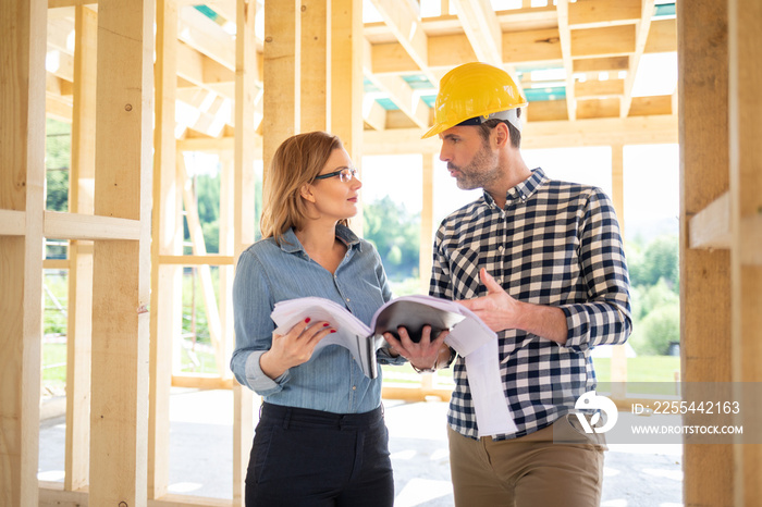 Female investor meeting with architect or engineer on construction site of her new house looking at blueprints