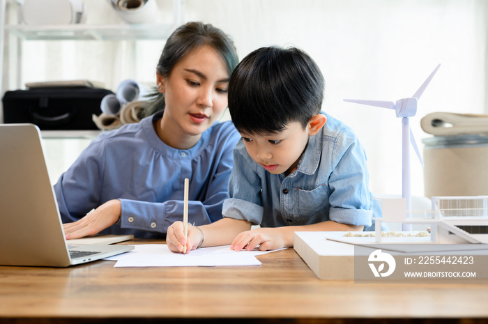 Little kid son practicing pencil drawing and writing under mother’s control, While Young Asian mother is an architect spending time with her little kid son, Mother helping son, Homeschool concept