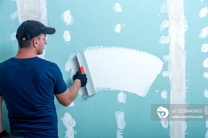 Worker applying putty on drywall