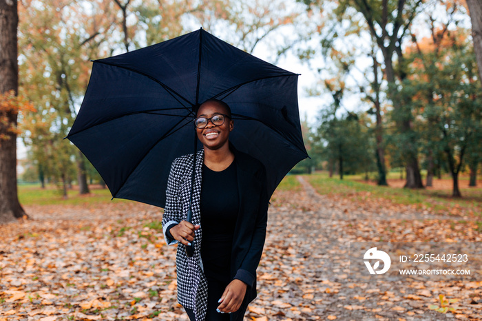 African American businesswoman with umbrella outdoors.