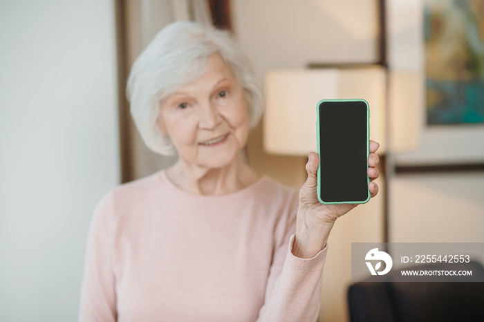 Gray-haired senior woman with a smartphone in hands