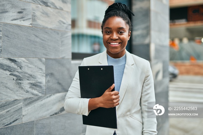 Young african american businesswoman smiling happy holding clipboard at the city.