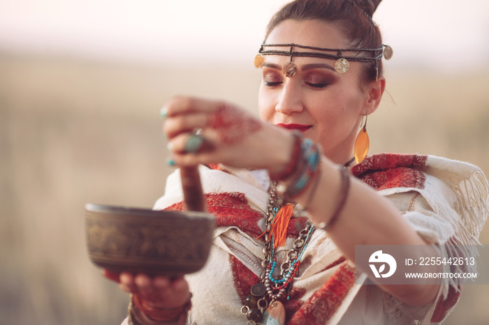 concept. Woman playing a Tibetan bowl. Pregnant woman doing yoga in the field at sunset.