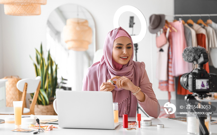 Muslim beauty blogger with cosmetic product recording video in dressing room