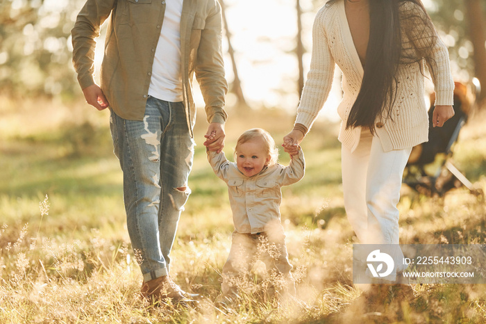 Having a walk. Happy family of father, mother and little daughter is in the forest