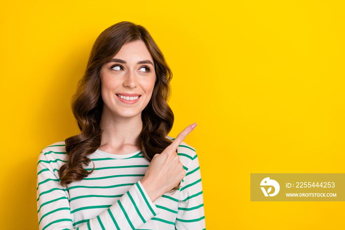 Closeup portrait of cute satisfied brown curly hair woman indicate finger empty space recommend brand offer isolated on yellow color background