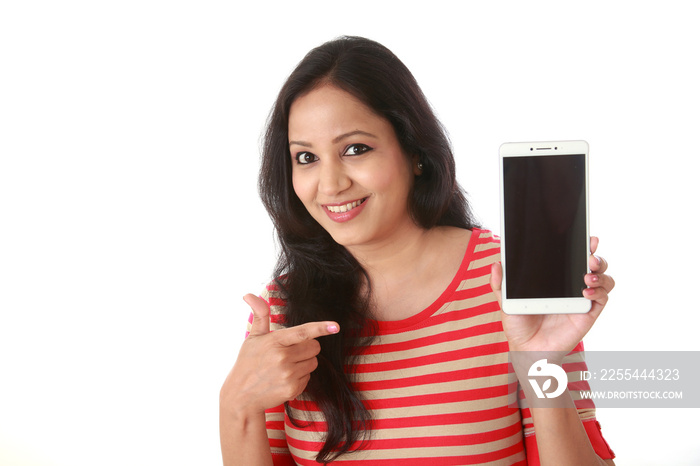 Young woman holding mobile phone against white background