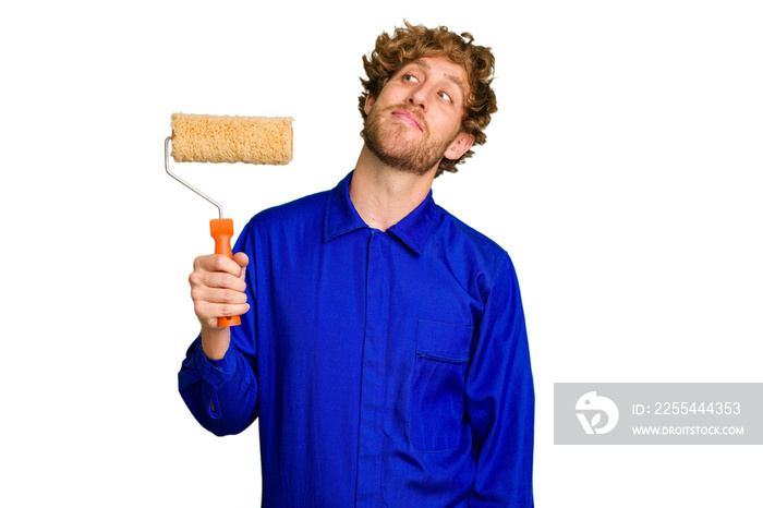 Young painter man holding a roll isolated on white background dreaming of achieving goals and purposes