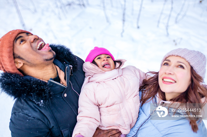 multicultural happy family catches snowflakes by mouth