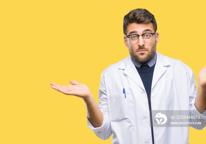 Young handsome man wearing doctor, scientis coat over isolated background clueless and confused expression with arms and hands raised. Doubt concept.