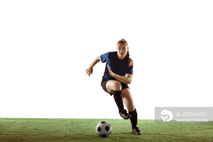 Young female soccer or football player with long hair in sportwear kicking ball for the goal, training on white studio background. Concept of healthy lifestyle, professional sport, motion, movement.