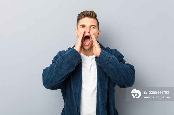 Young caucasian man wearing pajama shouting excited to front.