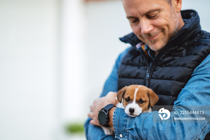 a man holding his little puppy Jack Russell in his arms