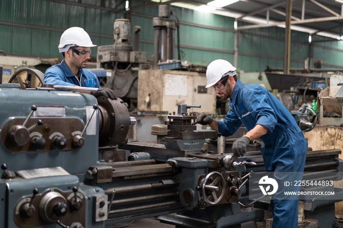 Industrial engineers in safety uniforms wearing white safety helmets are inspecting work by tools.  and on the job training he works in industrial machinery.