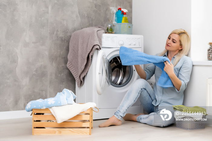 A young housewife with washing machine and clothes. Washing day.