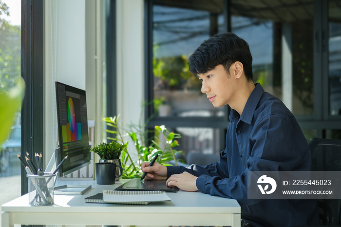 Young asian male graphic designer working  with color swatch samples at modern office.