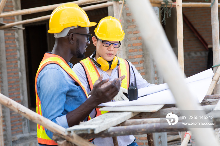 Professional Construction and  Engineer team Working on workplace. Professional black architect and construction worker working look at blueprint plan on site.