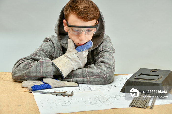 A young welder examines an assembly drawing before work.