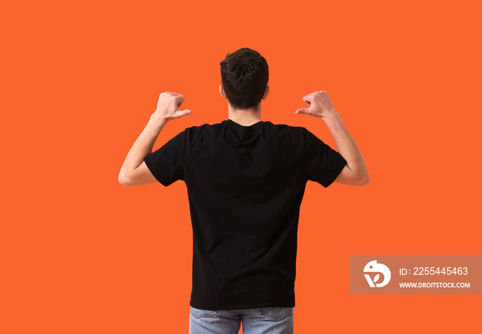 Handsome young man in stylish t-shirt on color background, back view