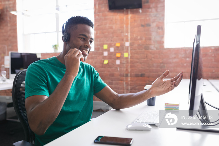 African american businessman having video call sitting in front of computer using headphones