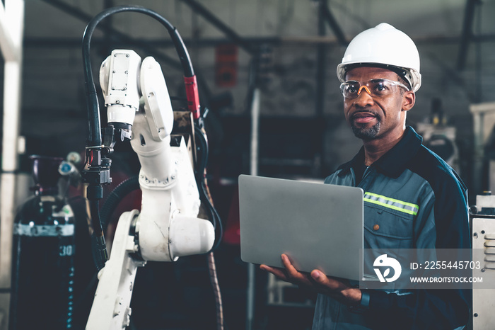 African American factory worker working with adept robotic arm in a workshop . Industry robot programming software for automated manufacturing technology .