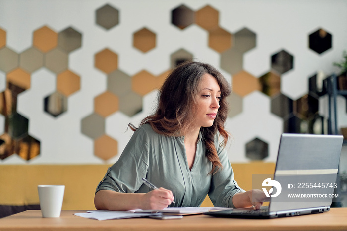 Young woman working from home office. Freelancer using laptop and the Internet. Workplace in living room.