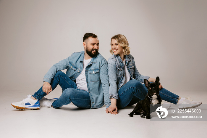 couple sitting on the floor,  happy couple with french dog on white background.