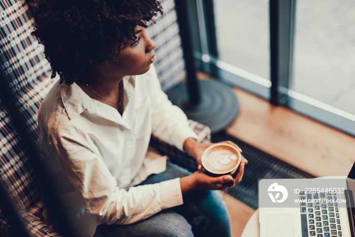 Beautiful lady looking aside and holding cup of coffee in hands