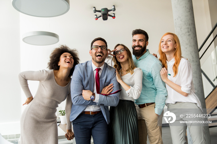 Young happy business people letting the drone camera to fly over the office and having fun