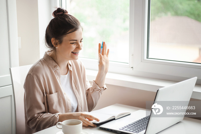 Woman speaking, looking at laptop making notes, girl student talking by video conference call, online training, e-coaching concept. Hand raised to answer. Covid