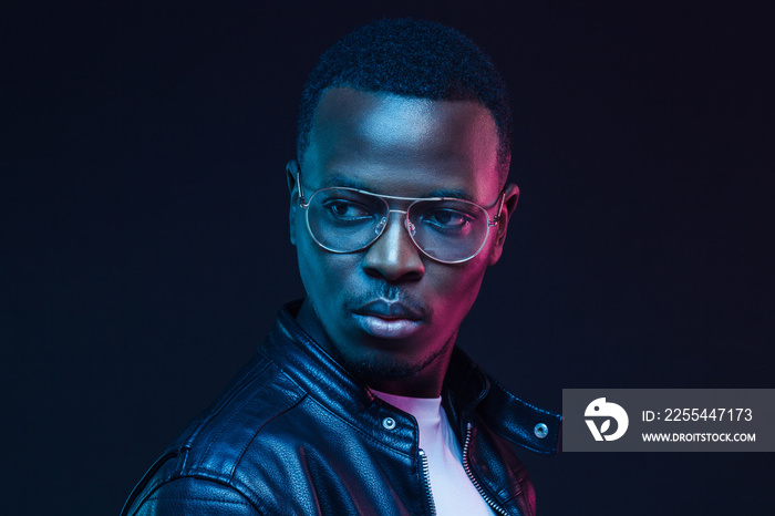 African guy in tranparent glasses and black leather jacket looking sidewards