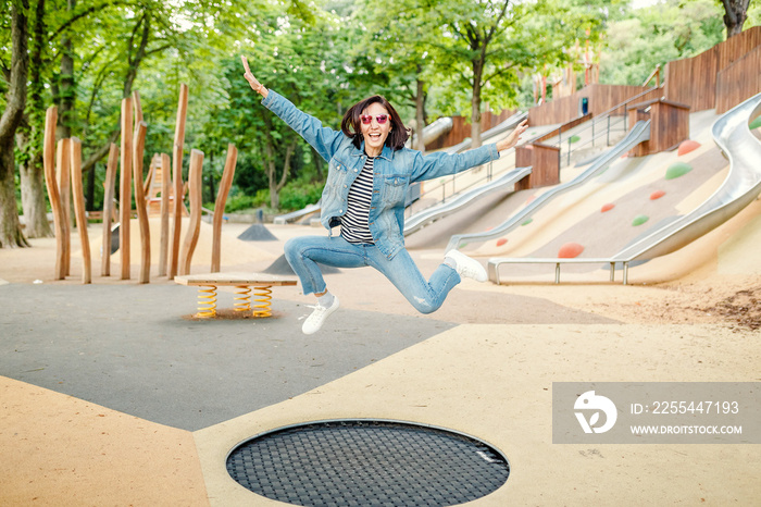 Happy girl having fun jumping on a trampoline at the outdoor modern playground